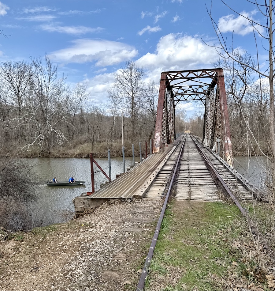 An old railway bridge stretches across the James River as a kayaker passes underneath.