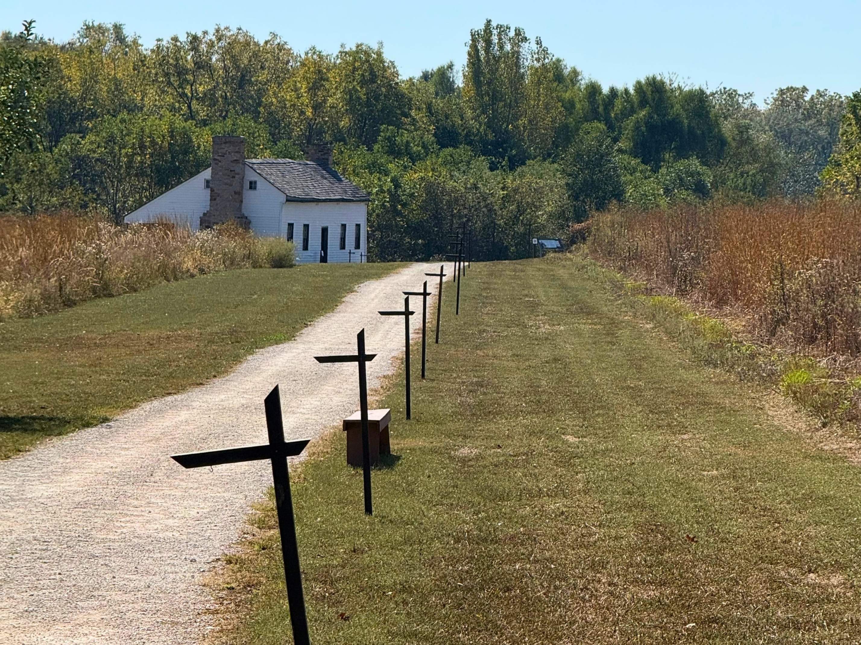 The Nathan and Olive Boone Homestead in Ash Grove, Missouri is nestled in a trimmed field of grass, with a path leading to it.